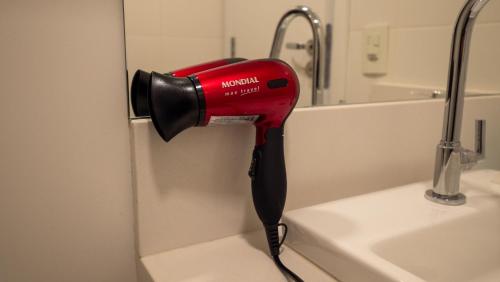 a red hairdryer hanging on a wall next to a sink at Apezinho Moema in Sao Paulo