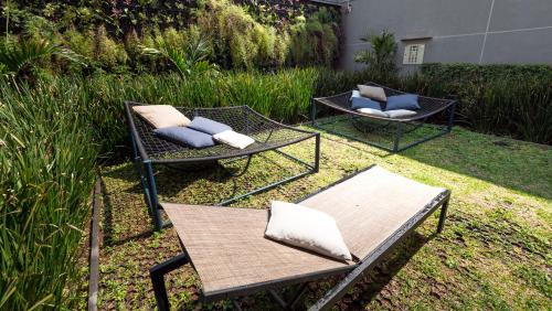 a patio with two chairs and a table with pillows at Apezinho Moema in Sao Paulo