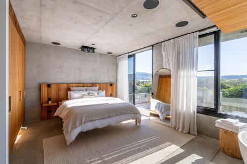 a bedroom with a large bed and large windows at Bunker House, Gerringong in Gerringong