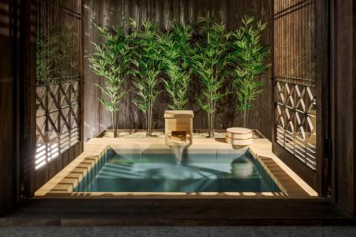 a jacuzzi tub in a room with plants at ROJIYU Kyoto in Kyoto