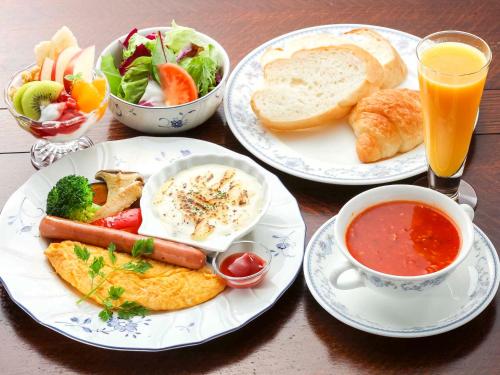 un tavolo con tre piatti di cibo e una tazza di succo di ペンションMoonLight a Fujikawaguchiko