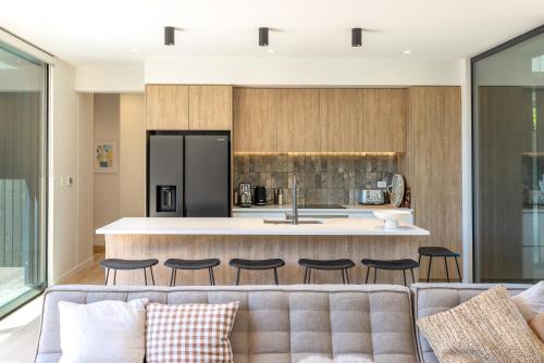 a living room with a couch and a kitchen at Wavesong Whakaaio 11D, 100 metres to Onetangi Beach - Be My Guest in Onetangi