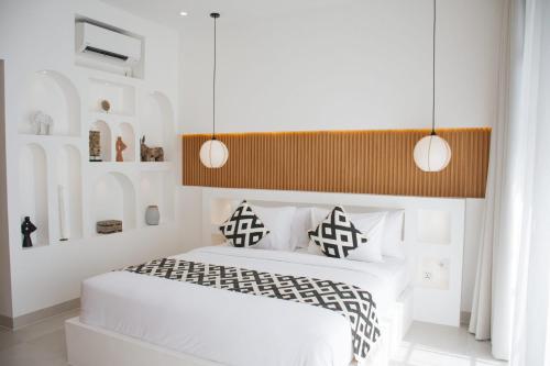 1 dormitorio con cama blanca y almohadas blancas y negras en Brand New Designer 1BR Villa, en Canggu