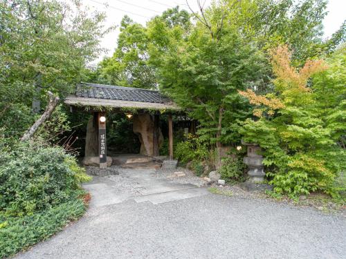 a small building with a gate in the trees at Yufuin Besso Shikisai Hotel in Yufuin