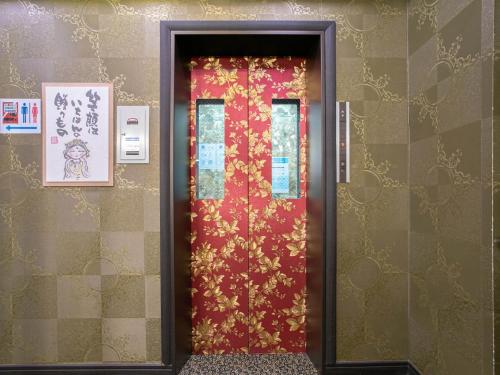 a red door with gold flowers on a wall at Yufuin Besso Shikisai Hotel in Yufuin