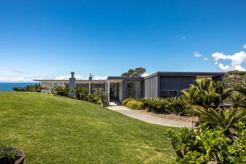 une maison sur une colline avec une pelouse verte dans l'établissement Marino Ridge, à Oneroa