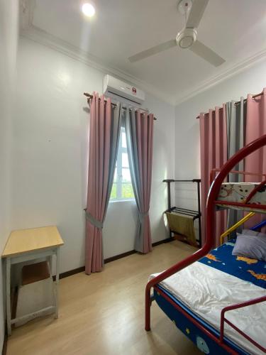 a bedroom with pink curtains and a bed and a table at Homestay Tok Ma 2 Gong Chempedak Marang in Marang
