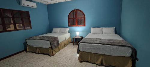 two beds in a room with blue walls at El Paraíso Escondido in San Luis