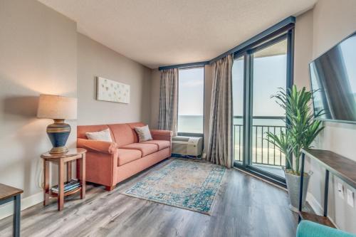 a living room with a couch and a large window at Enjoy Paradise Oceanfront Suite, Dogs OK! 908 in Myrtle Beach