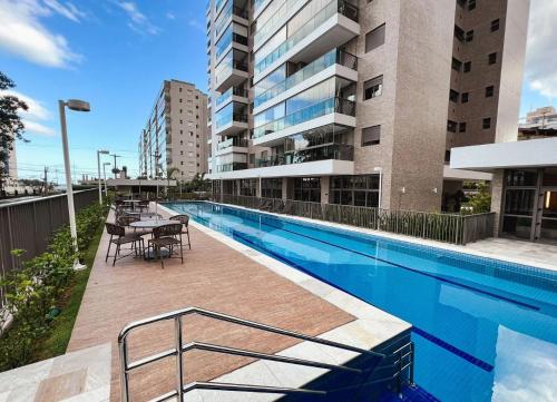 a swimming pool with a table and chairs next to a building at Apartamento Tulum Bertioga in Bertioga