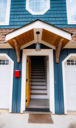 a blue house with a yellow door and stairs at Urban Nest Guest House in Charlotte
