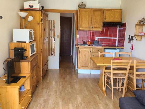 une cuisine avec des armoires en bois et une table avec un micro-ondes dans l'établissement Studio cabine cosy pour 4 au pied des pistes - FR-1-689-140, à Villard-de-Lans