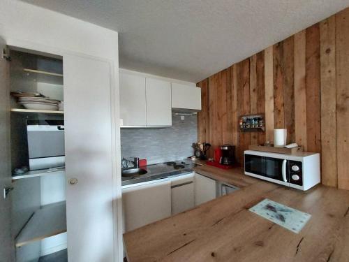 La cuisine est équipée de placards blancs et d'un four micro-ondes blanc. dans l'établissement Appartement 2 pièces avec balcon pour 6 personnes à La Plagne-Tarentaise - FR-1-353-147, à La Plagne Tarentaise