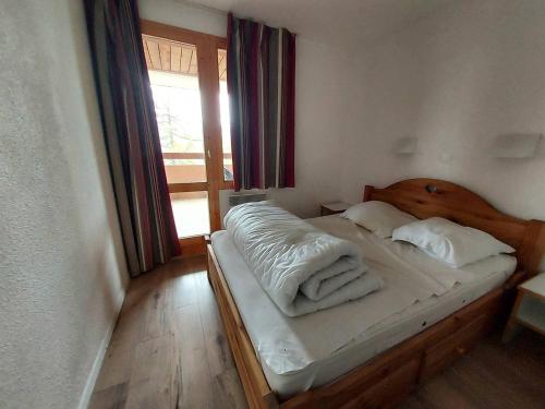 une chambre avec un lit avec des draps blancs et une fenêtre dans l'établissement Appartement 2 pièces avec balcon pour 6 personnes à La Plagne-Tarentaise - FR-1-353-147, à La Plagne Tarentaise