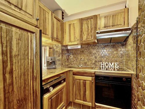 une cuisine avec des armoires en bois et un four à plaques de cuisson dans l'établissement Courchevel 1850, Skis aux pieds, 4 pers, 2 pièces, Parking, WiFi - FR-1-575-225, à Courchevel