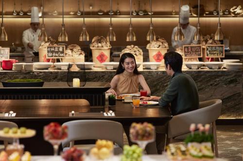 a man and woman sitting at a table in a restaurant at InterContinental Shenzhen WECC by IHG in Shenzhen