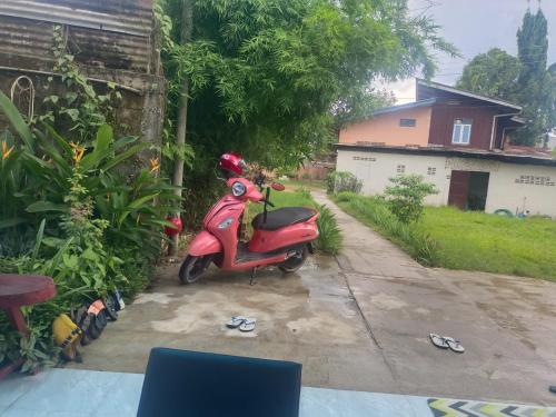 a red scooter parked in the driveway of a house at Champa House in Vang Vieng