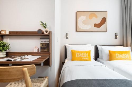 two beds in a room with a table and a desk at Dash Living on Queen's in Hong Kong