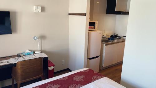 a small room with a desk and a kitchen at Naha airport hotel in Takara