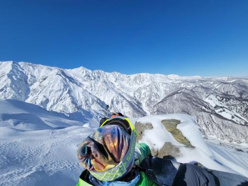 a person laying on top of a snow covered mountain at Azumino Salon in Azumino