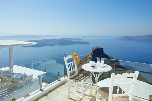 Una mesa y sillas en un balcón con vista al mar. en Imerovigli Iliovasilema Villa, en Imerovigli