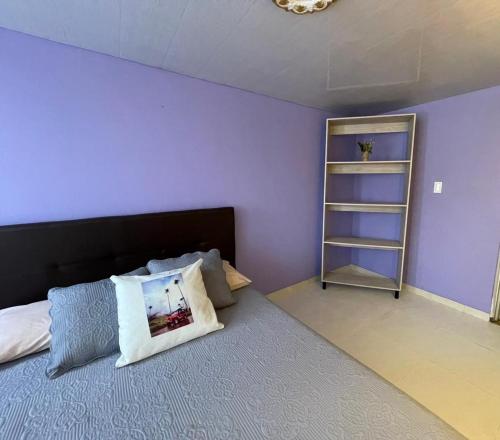 a bedroom with a bed with purple walls and a shelf at APARTAMENTO VACACIONAL in Santa Rosa de Cabal