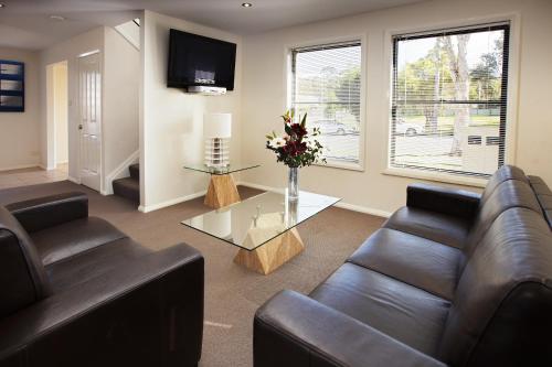 a living room with a couch and a table with flowers at Charlestown Terrace Apartments in Newcastle
