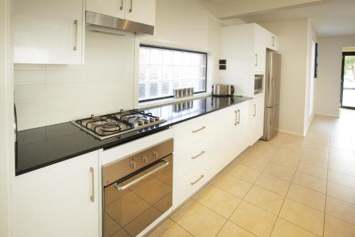 a kitchen with white cabinets and a stove top oven at Charlestown Terrace Apartments in Newcastle