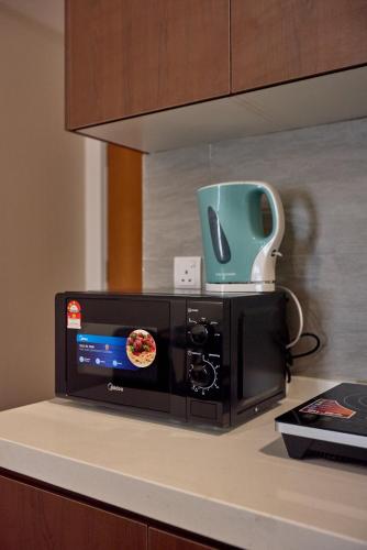 a microwave on a counter with a green bowl on top at Sunsuria Forum SOHO & Residence Suites Setia Alam by MOKA in Shah Alam