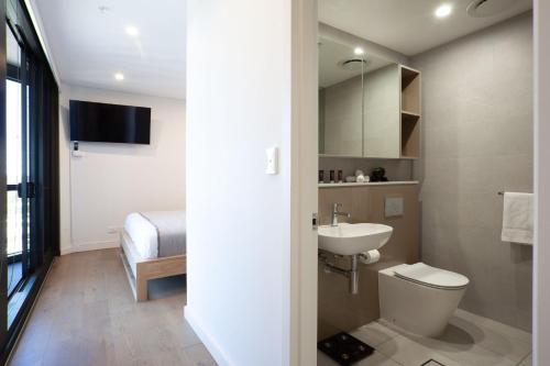 a bathroom with a toilet and a sink and a bed at Modern Splendour, Macquarie Park I90 in Sydney
