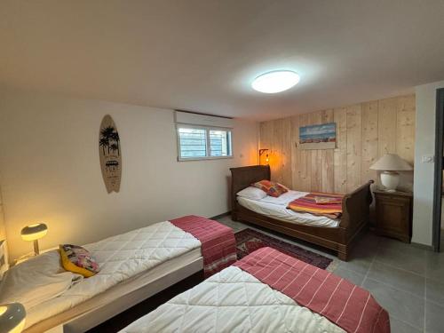 a bedroom with two beds and a table with a lamp at Le Phare in Agon Coutainville