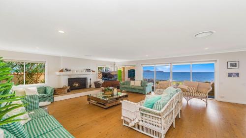 a living room with chairs and a fireplace and the ocean at Absolute Beachfront Beauty - Pearl Beach in Pearl Beach