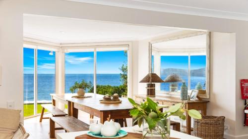 a living room with a table and views of the ocean at Absolute Beachfront Beauty - Pearl Beach in Pearl Beach