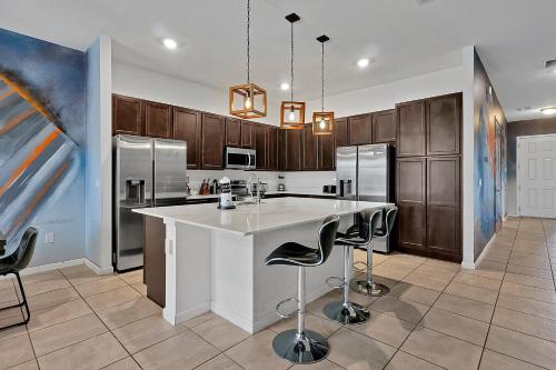 a kitchen with a large white island with bar stools at Luxury 12-BR Villa w/ Pool & Resort Amenities Near Disney in Kissimmee