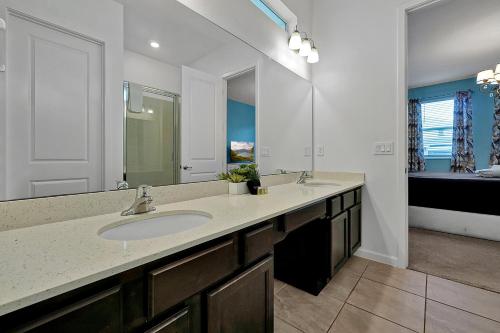 a bathroom with a sink and a large mirror at Luxury 12-BR Villa w/ Pool & Resort Amenities Near Disney in Kissimmee