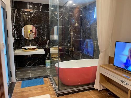 a bathroom with a tub and a shower with a television at Love Hotel Hóc Môn in Ho Chi Minh City
