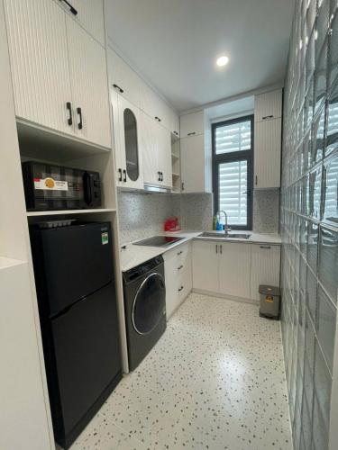 a kitchen with white cabinets and a black dishwasher at SH17 Villa Hải Phòng in Hai Phong