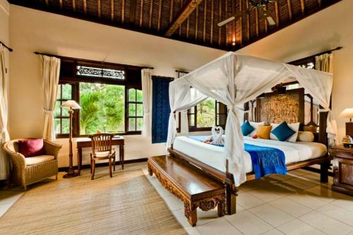a bedroom with a canopy bed and a desk at Fullara 1 BR Suite With Rice Field View ZN240 in Ubud