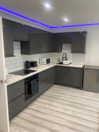 a kitchen with black cabinets and white tile floors at Lovely Modern studio flat with jacuzzi bath free parking in Stanwell