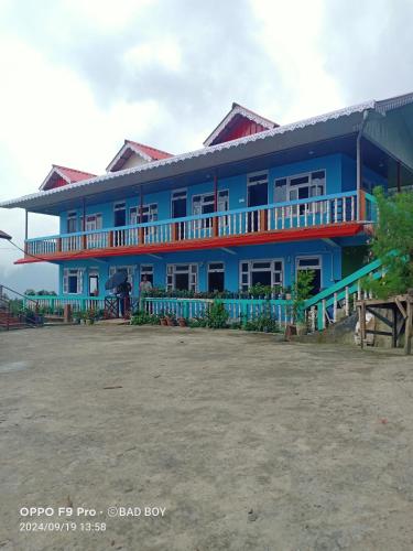 a large blue building with a lot of windows at Rishop Mountain Homestay in Rishop