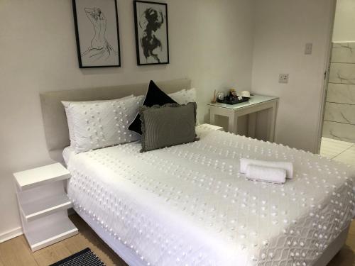 a bedroom with a large bed with white sheets and pillows at Bluebanana Lodge in Mthatha