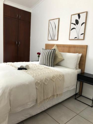 a bedroom with a large white bed with a table at Bluebanana Lodge in Mthatha