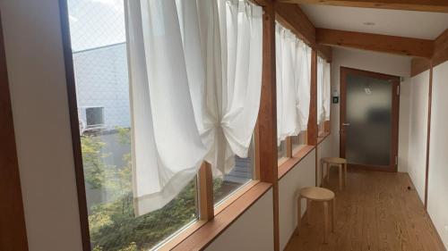 a room with a window with white curtains at WGJ Hostel Kyoto in Nishi-kujō-Toriiguchichō