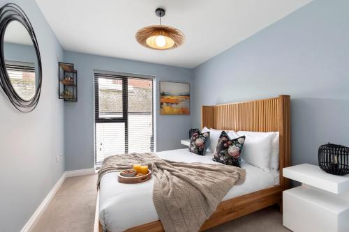 a bedroom with a bed with blue walls and a mirror at Elliot Oliver - Beautiful Two Bedroom Apartment With Parking in The Docks in Gloucester