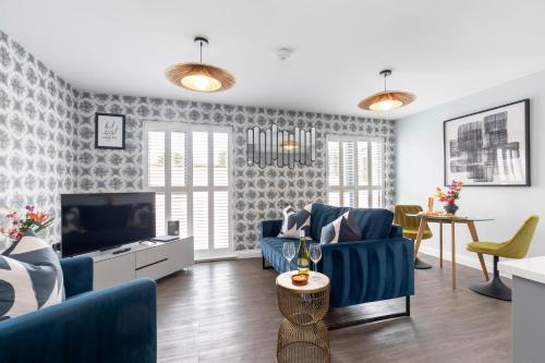 a living room with blue chairs and a television at Elliot Oliver - Charming One Bedroom Apartment With Parking in The Docks in Gloucester