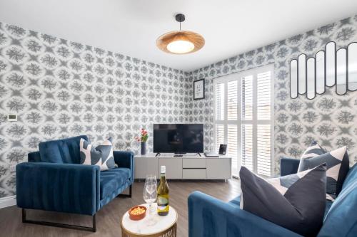 a living room with blue chairs and a tv at Elliot Oliver - Charming One Bedroom Apartment With Parking in The Docks in Gloucester