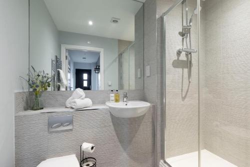 a bathroom with a sink and a shower with a mirror at Elliot Oliver - Charming One Bedroom Apartment With Parking in The Docks in Gloucester