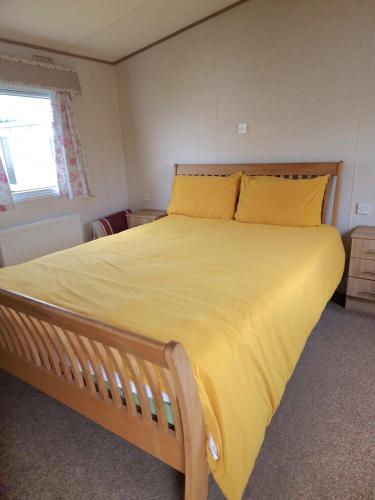 a bedroom with a large bed with yellow sheets at The Pearl - Deluxe Access Caravan in Skegness