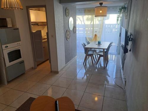 une cuisine et une salle à manger avec une table et des chaises dans l'établissement Le Bosquet, superbe rez de jardin, parking, clim,650m plage Grau d'agde, au Grau-dʼAgde