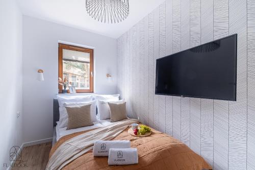 a bedroom with a bed with a flat screen tv on the wall at Krynica Morska - Nautikka Park z Siłownią i Salą Zabaw in Krynica Morska